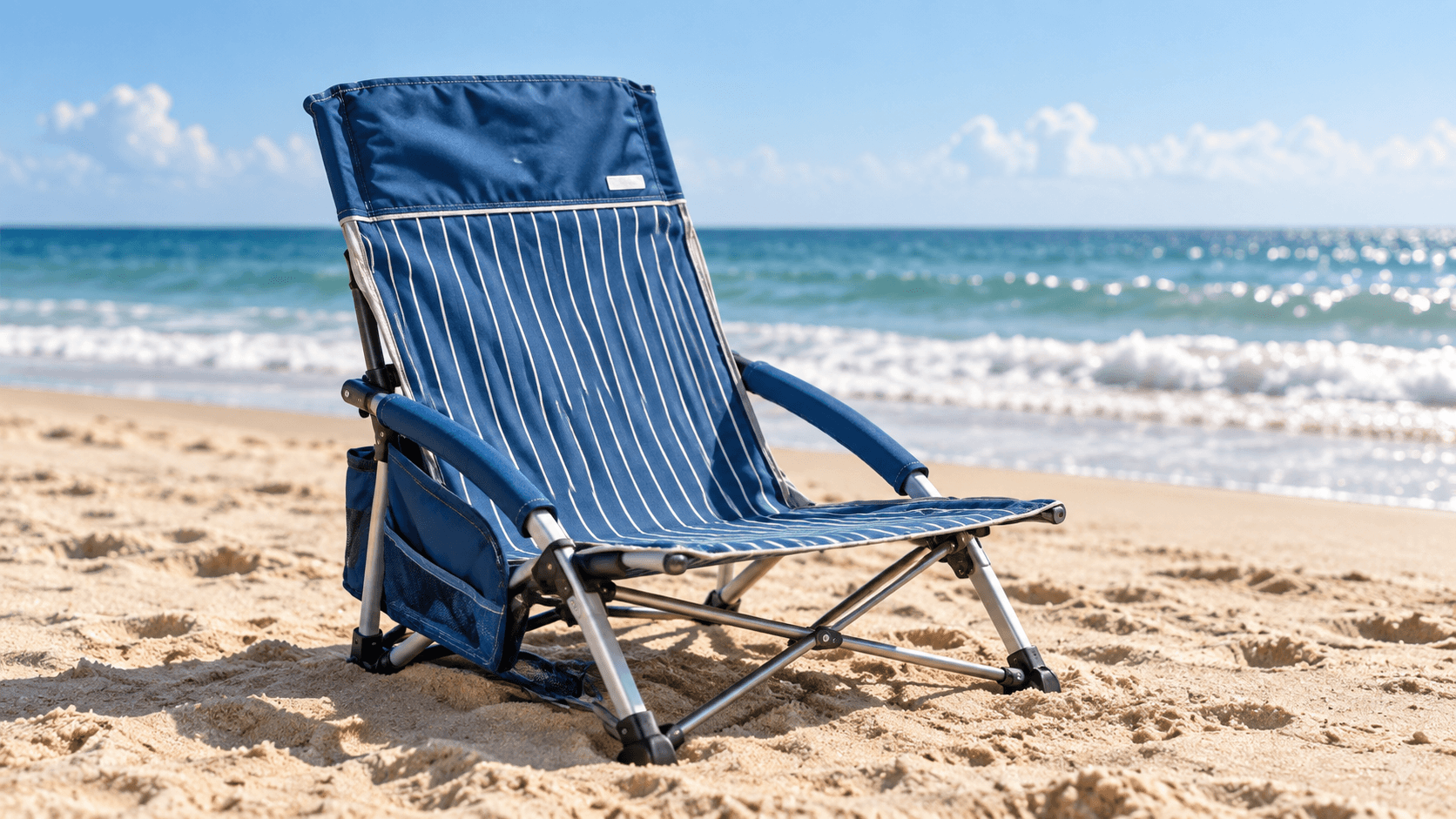 Blue and white striped low beach chair set up on the sand at the water's edge in Port Aransas
