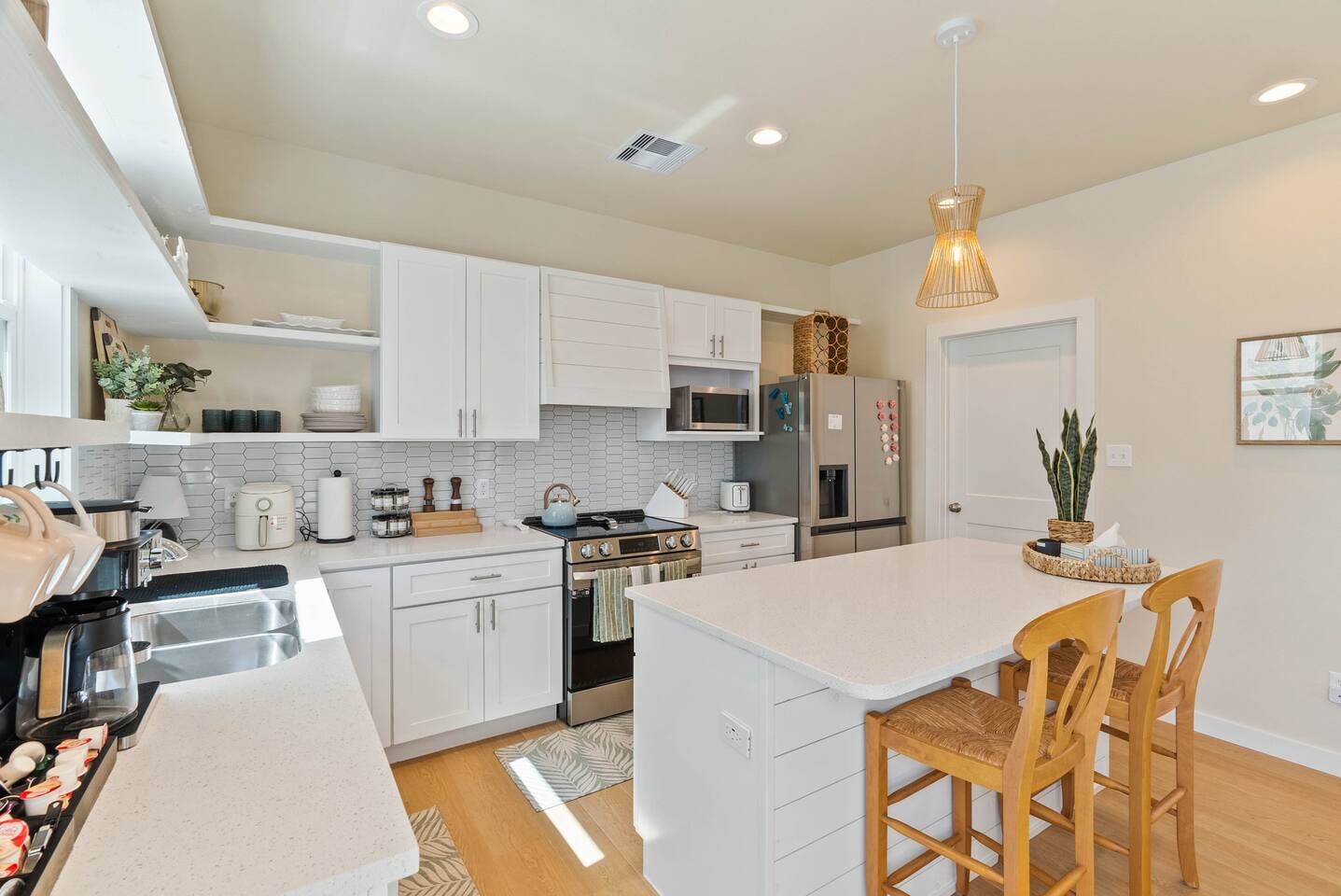 Another angle of the modern kitchen with stainless steel appliances and a cozy island seating area.