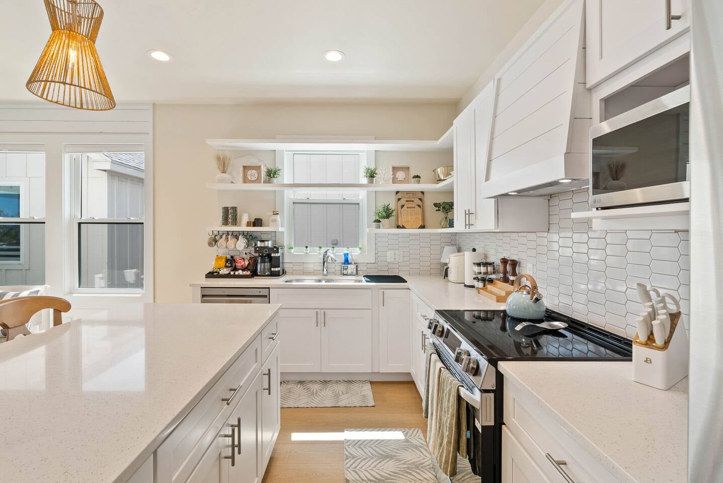 Gorgeous view of the crisp white kitchen with coffee bar and stylish open shelving, perfect for meals that feel like home.