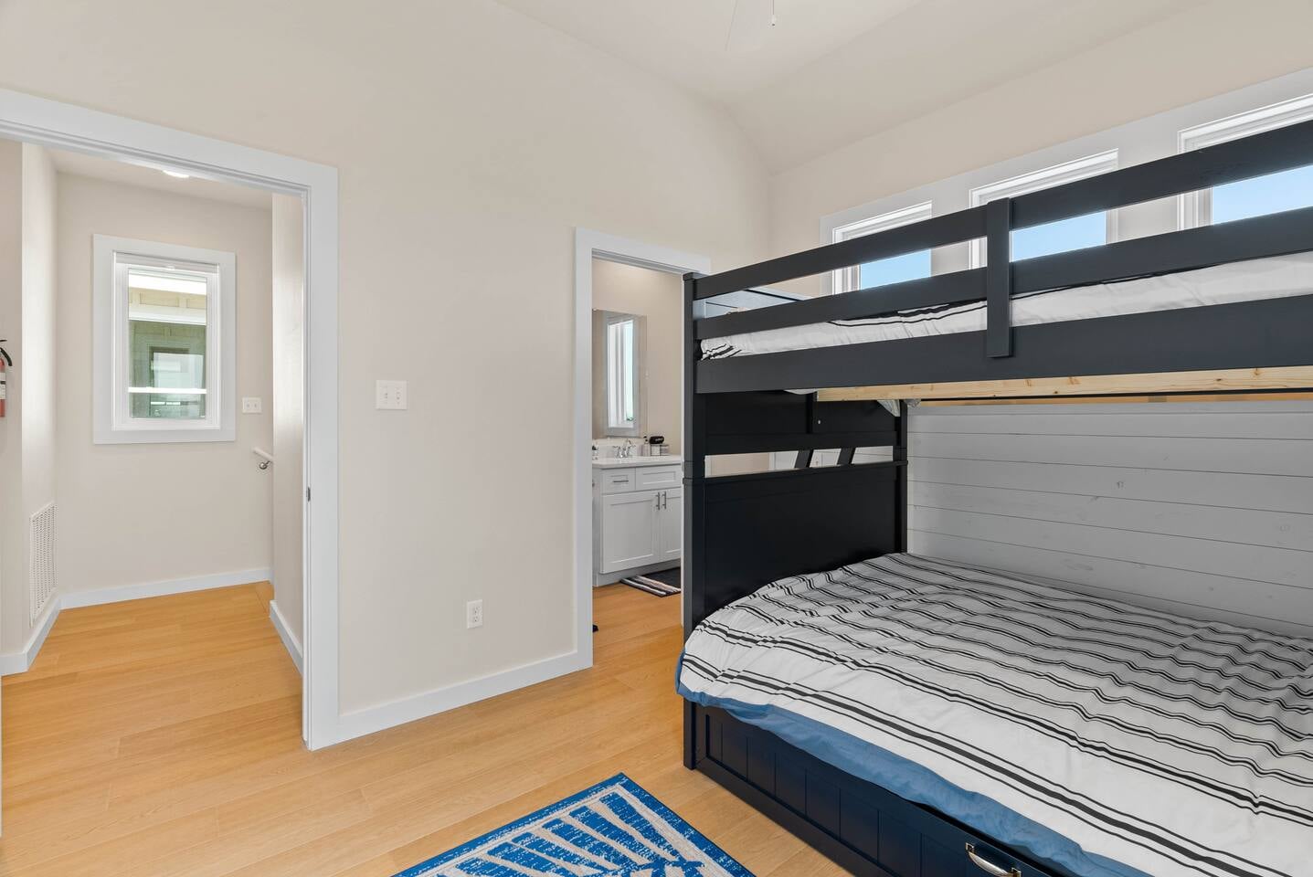 Another view of the 3rd-floor bunk room which offers two full-size beds and a twin trundle, plus a peak of the ensuite bathroom with a large bathtub, perfect for families and conveniently close to th