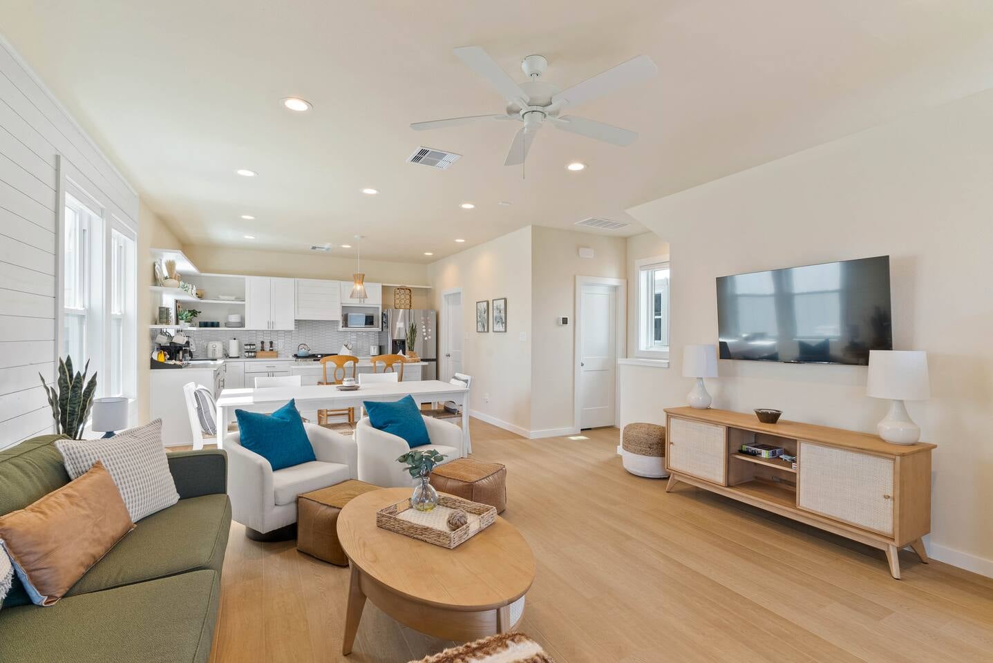 Another view of the bright and open living space with large smart TV, cozy seating, large dining area, and kitchen, perfect for gathering and relaxing together.