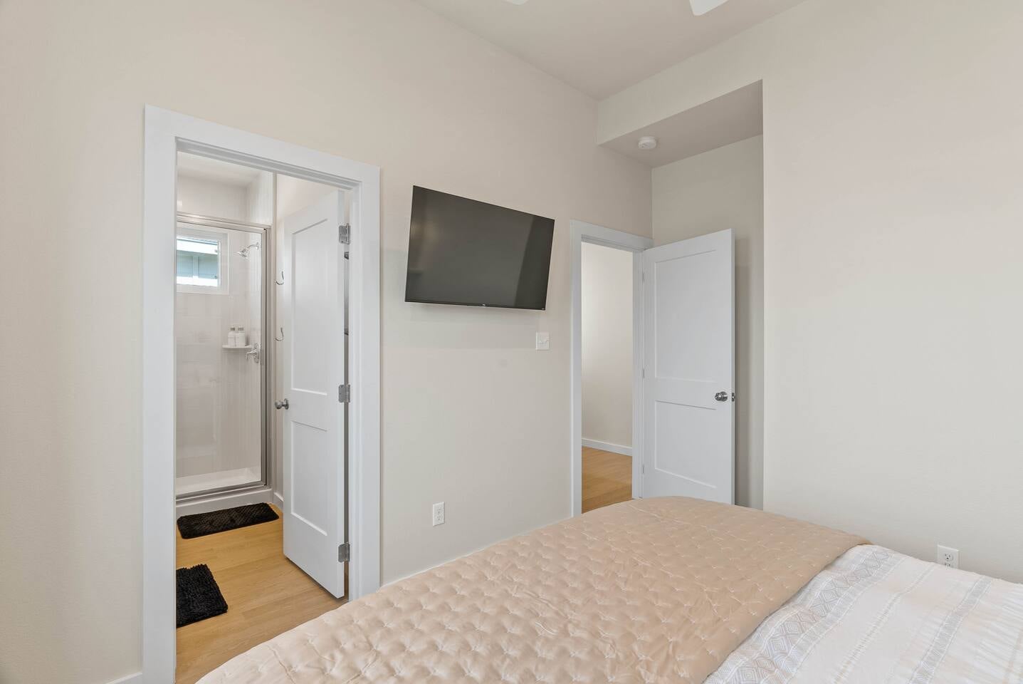 Another view of the 3rd floor master suite with wall-mounted smart TV, ensuite bathroom with a large shower, and direct access to the walk-in closet.
