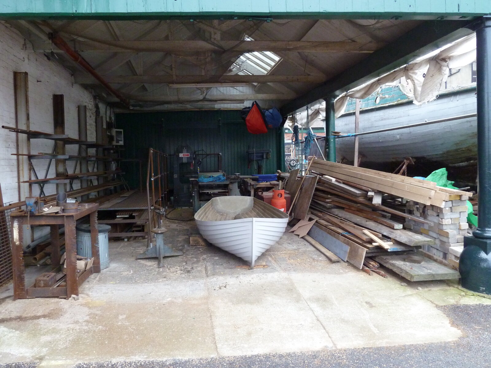 Wooden boats, hulls, and lumber inside an open boatbuilding workshop - representative of the hands-on restoration work at Farley Boat Works.